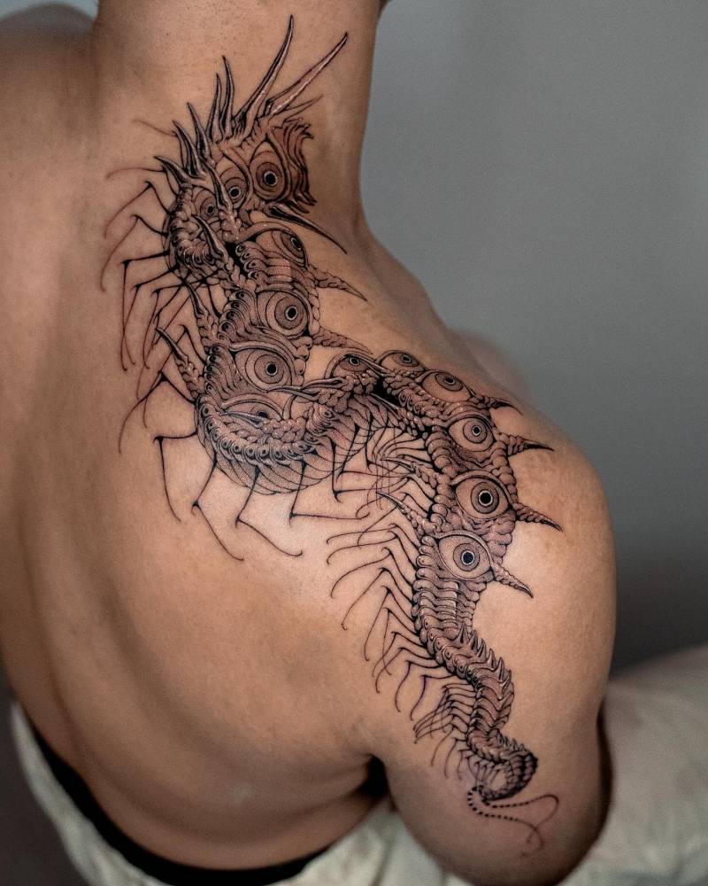 Eye centipede tattoo located on the top of shoulder, done in illustrative style.