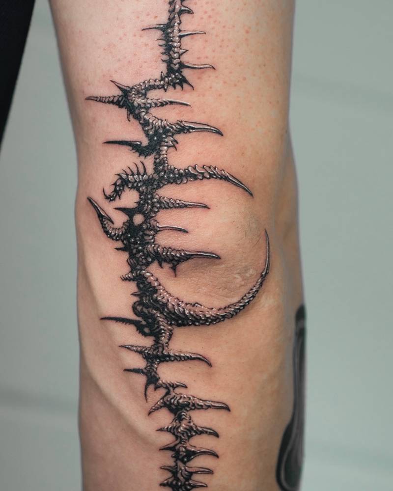 Crescent moon and thorns tattooed on the elbow, done in illustrative style.
