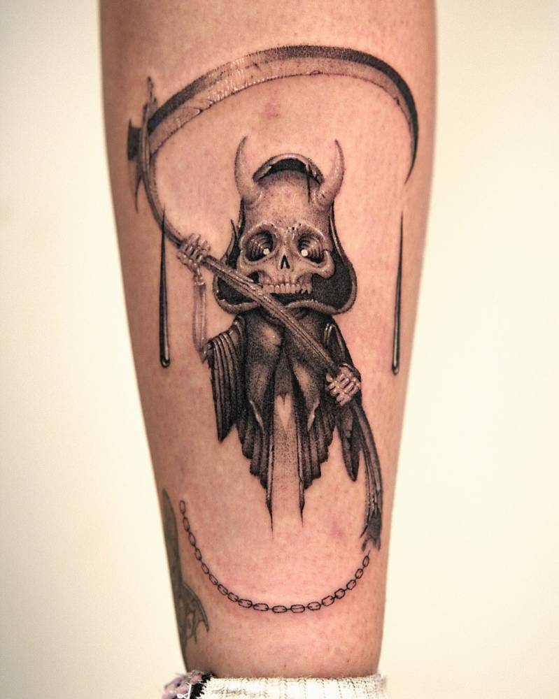 Cartoony style Grim Reaper tattoo located on the shin.
