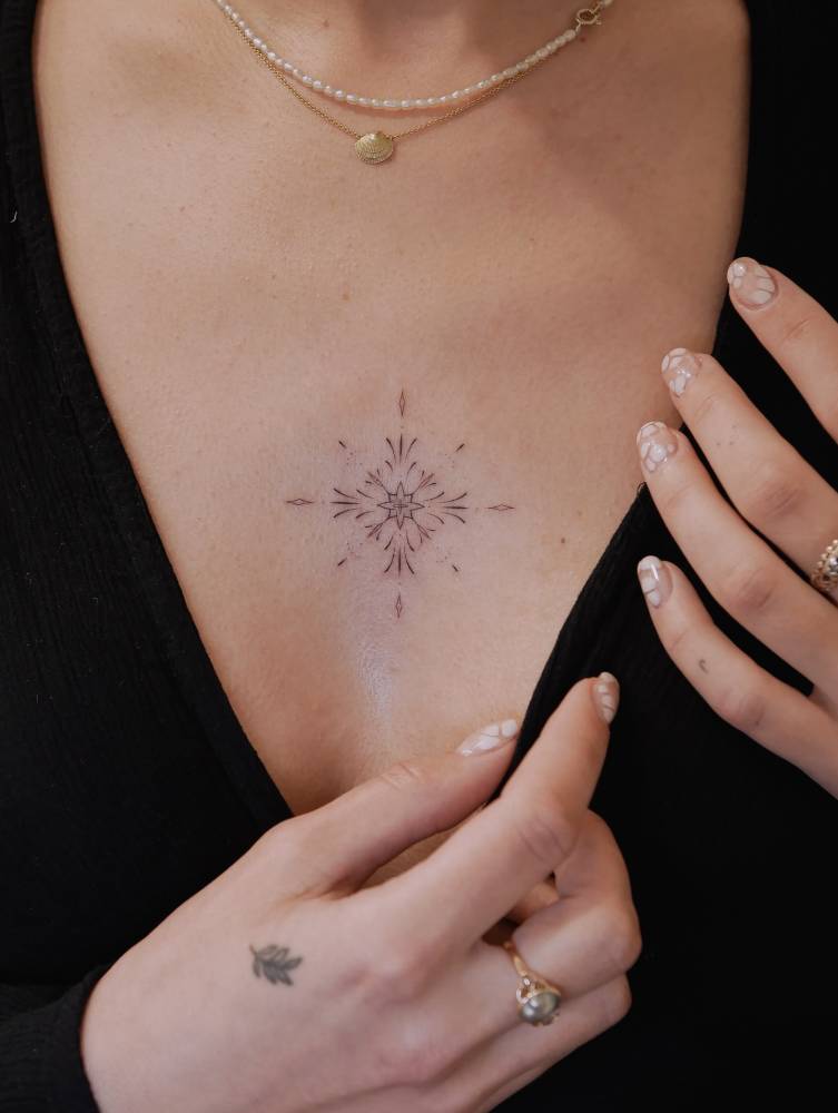 Ornamental tattoo in fine line style located on the sternum.