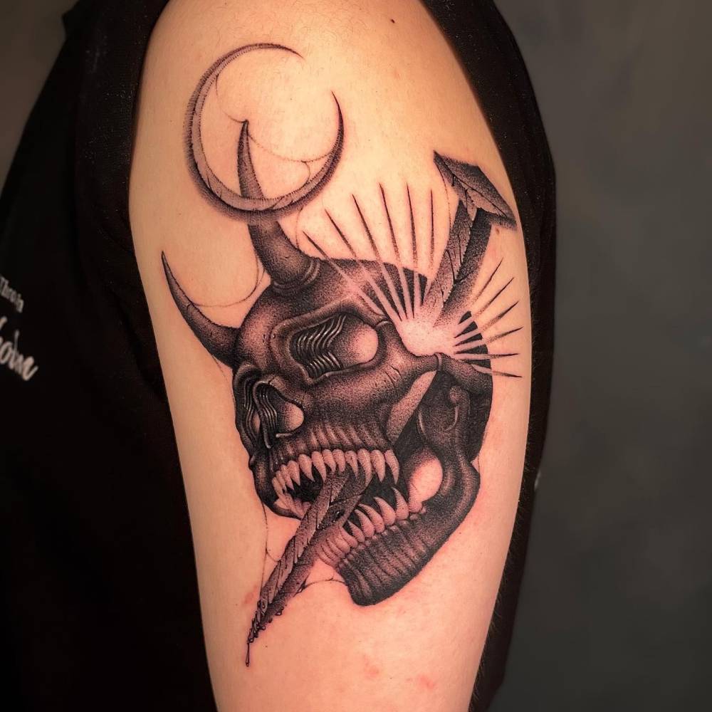Devil skull and nail tattoo located on the upper arm.