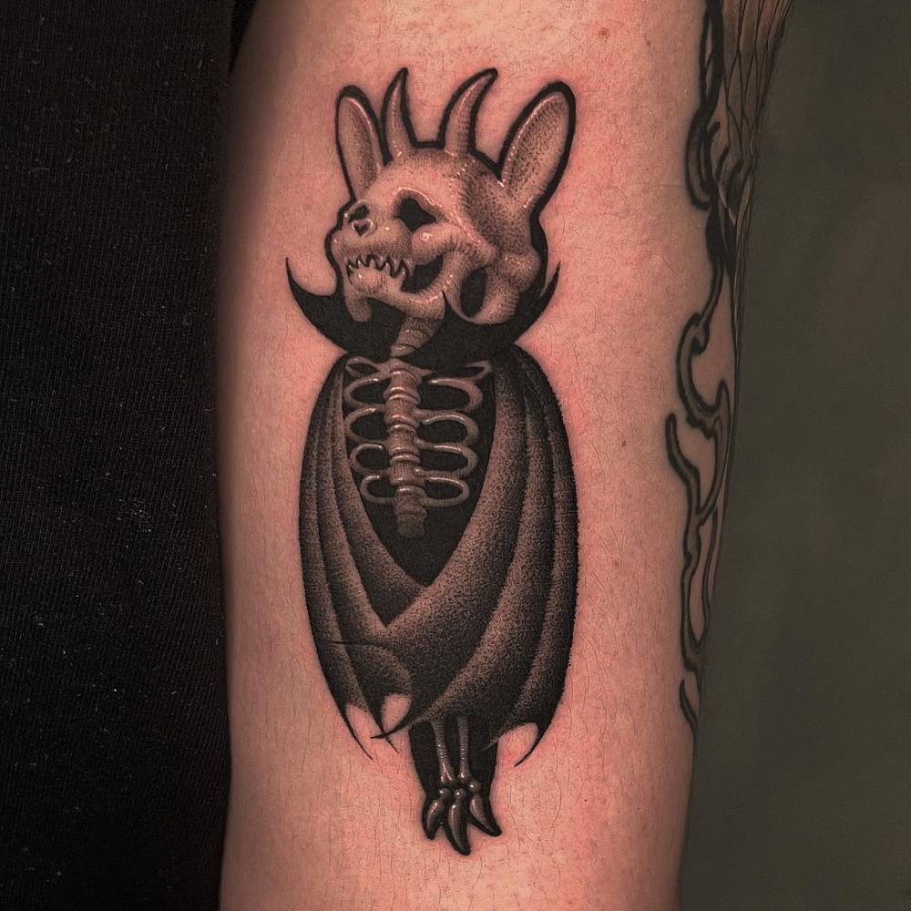 Skeleton bat tattoo located on the upper arm, illustrative style.