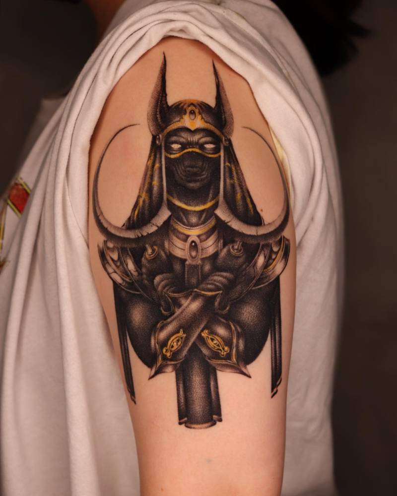 Anubis tattoo located on the upper arm, illustrative style (healed).