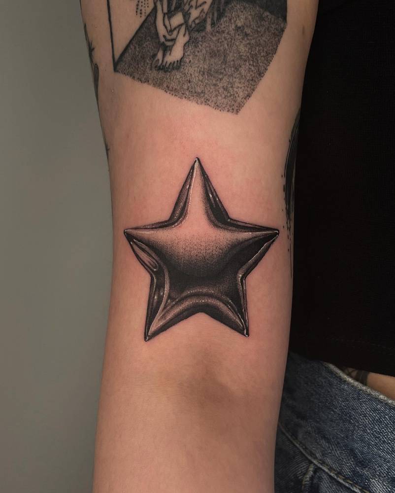 Metallic star balloon tattoo located on the bicep.