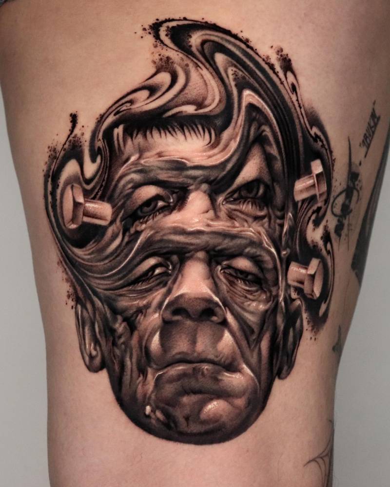 Frankenstein's monster tattoo in abstract style located on the thigh.
