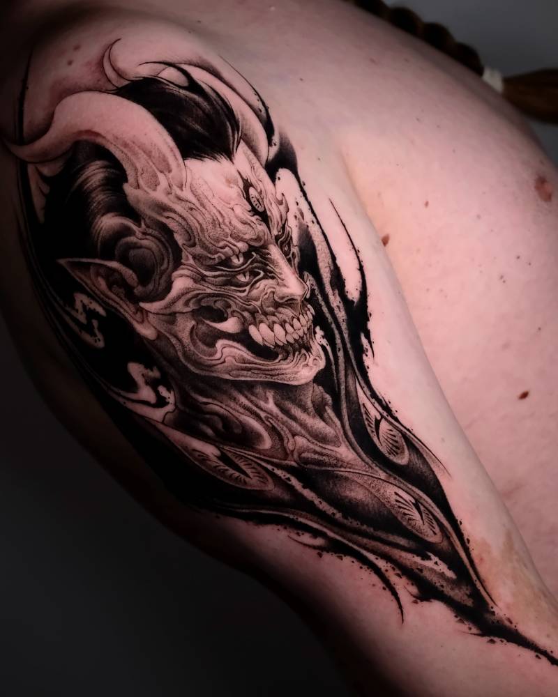 Devil tattoo in blackwork style located on the upper arm.