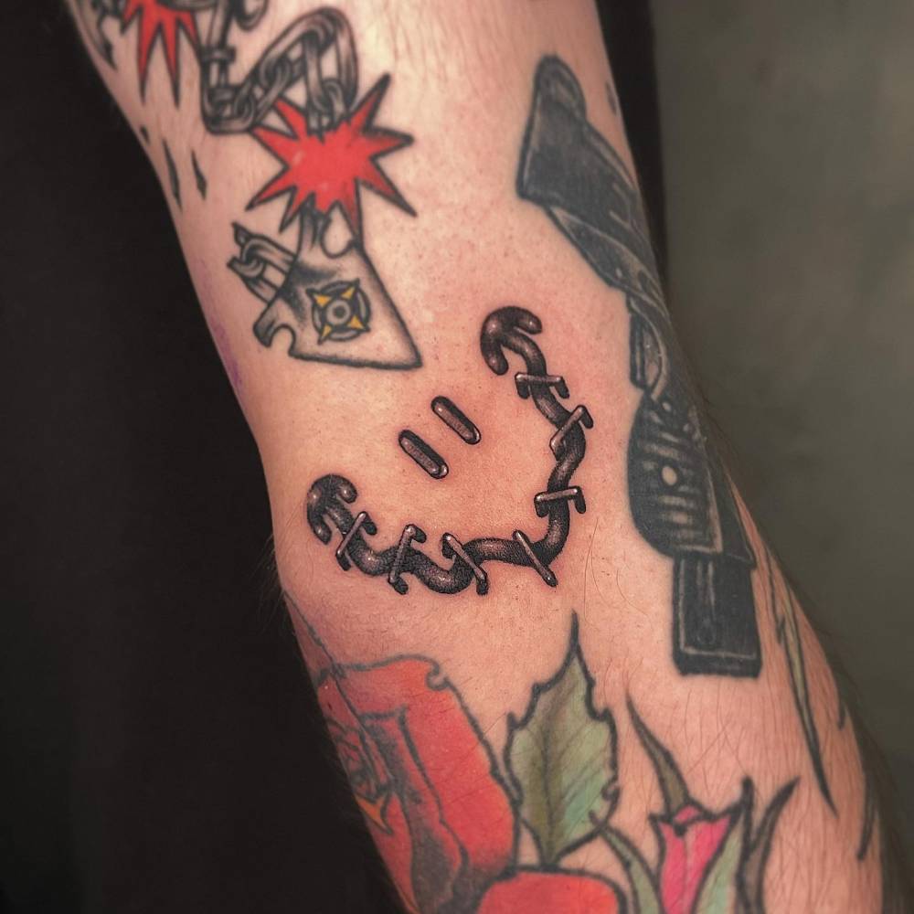 Smiley face gap filler tattoo located on the bicep.