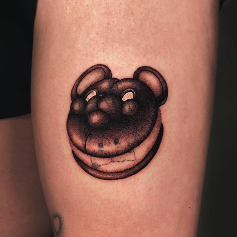 Bear macaron tattoo in illustrative style located on the thigh.