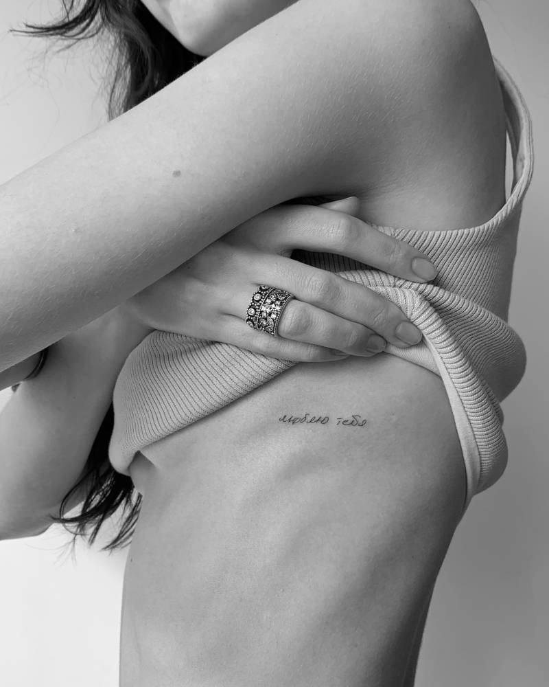 Russian lettering tattoo handwritten on the side boob.