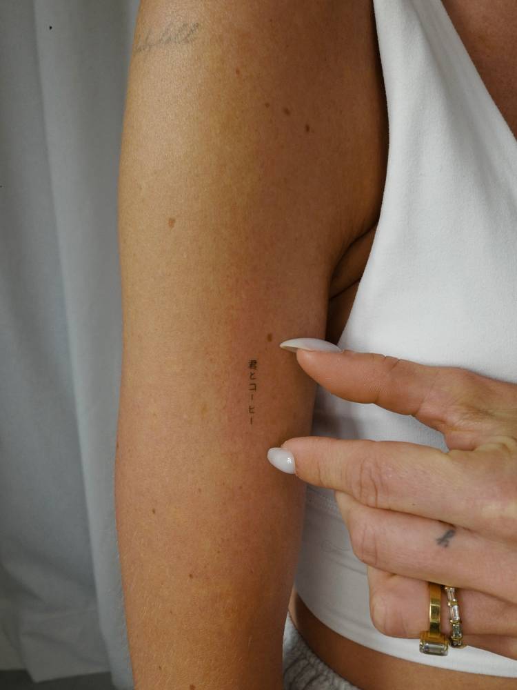 Tiny Japanese lettering tattoo located on the upper arm.