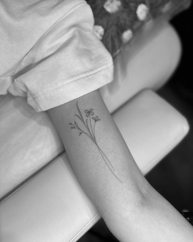 Flower bouquet tattoo placed on the inner arm, done in fine line style.