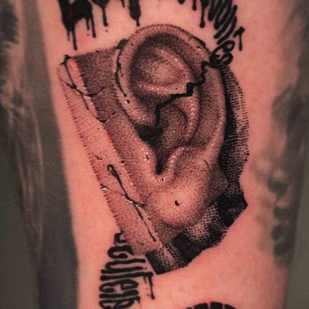 Dotwork style ear tattoo located on the upper arm.