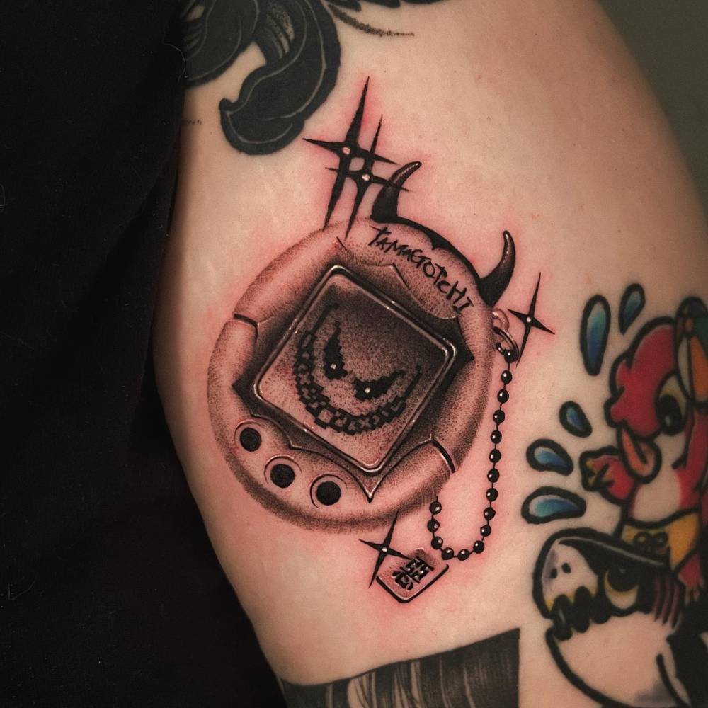 Illustrative style Tamagotchi tattoo located on the upper arm.