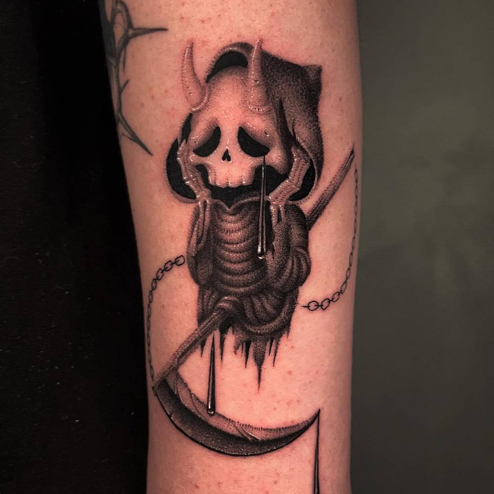 Cartoon style Grim Reaper tattoo located on the forearm.