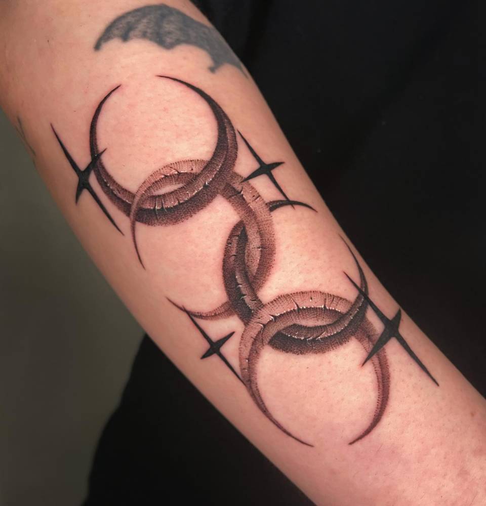 Crescent moons and stars tattooed on the forearm.