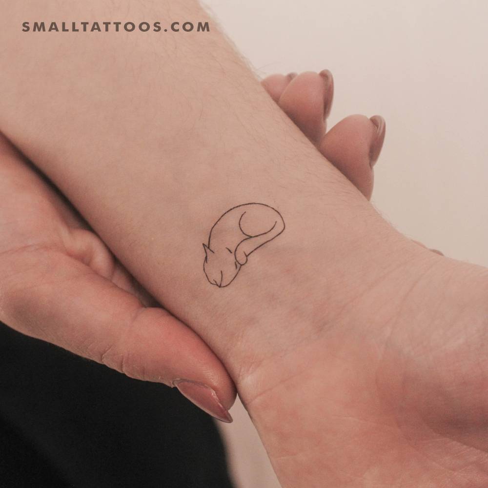 Fine line sleeping cat temporary tattoo located on the wrist.
