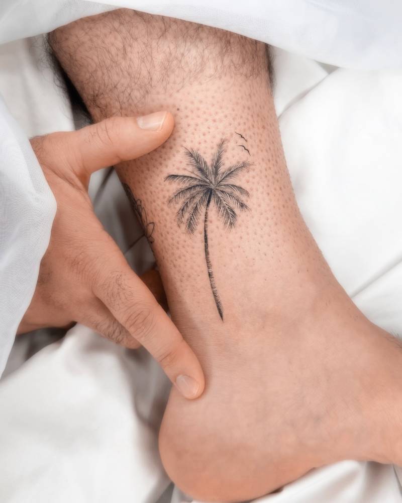 Micro-realistic style palm tree tattoo located on the ankle.
