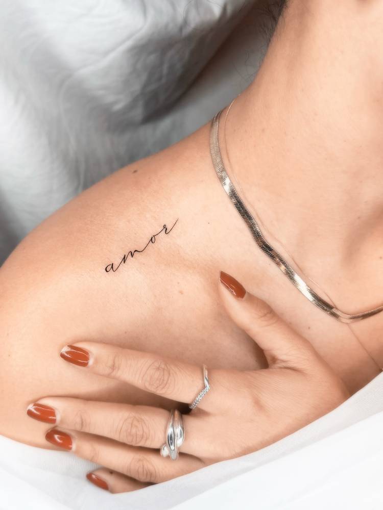 Lettering tattoo of the word "amor" located on the top of shoulder.