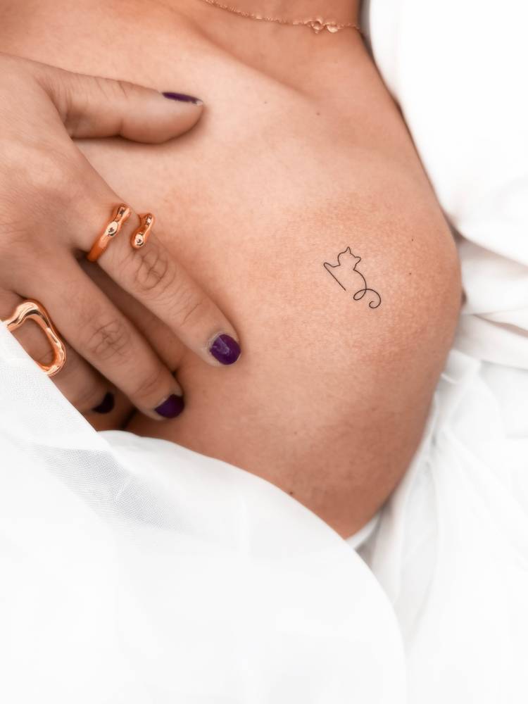 Minimalistic style one line cat tattoo located on the shoulder.