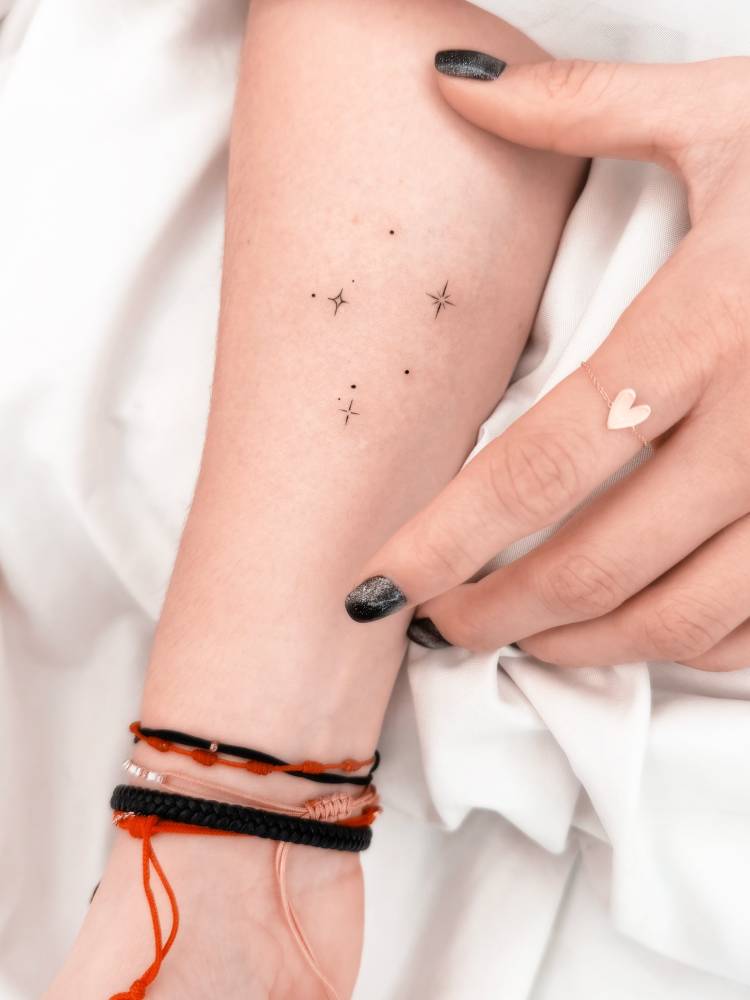 Sparkling stars tattoo in minimalistic style located on the inner forearm.