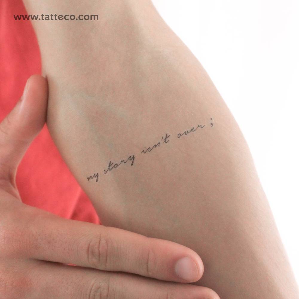 Handwritten font "my story isn't over" temporary tattoo located on the inner forearm.