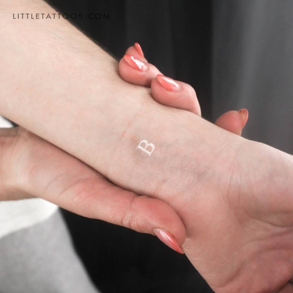 White letter "B" in serif font temporary tattoo placed on the wrist.