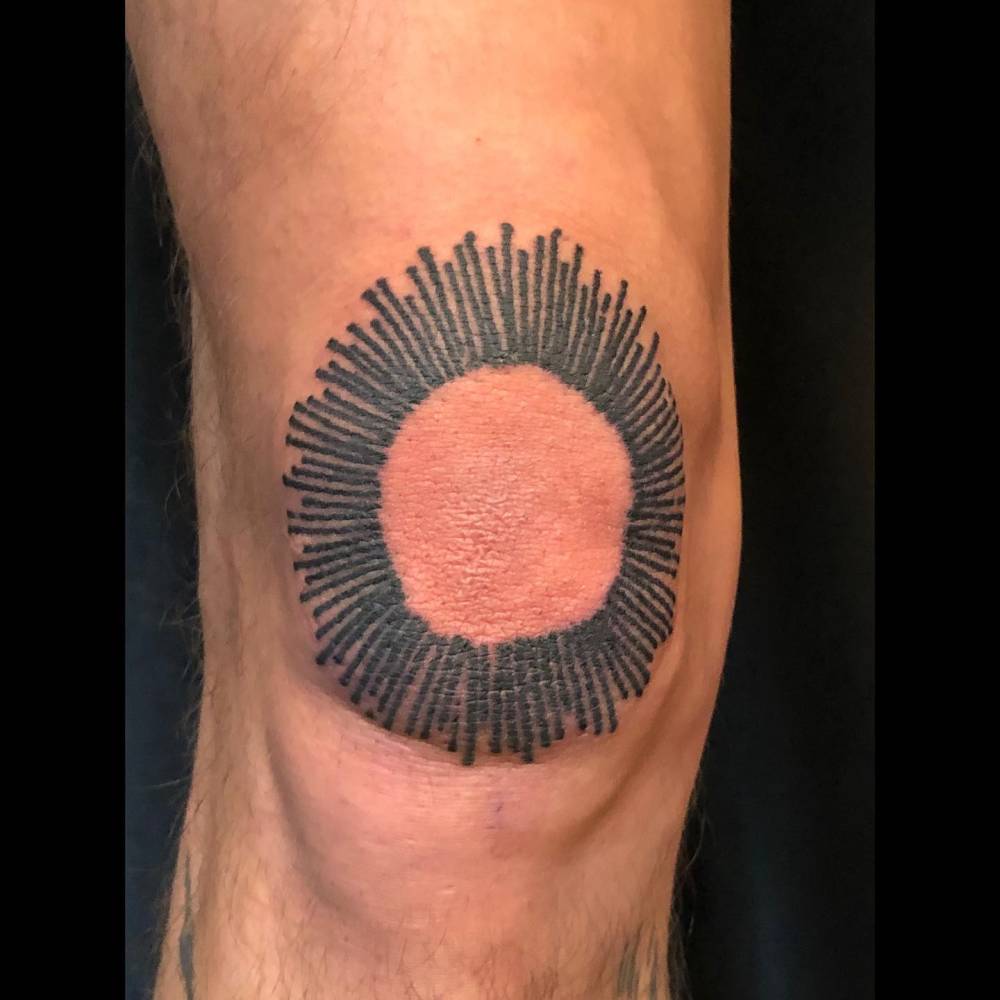 Blackwork style sun tattoo located on the knee.