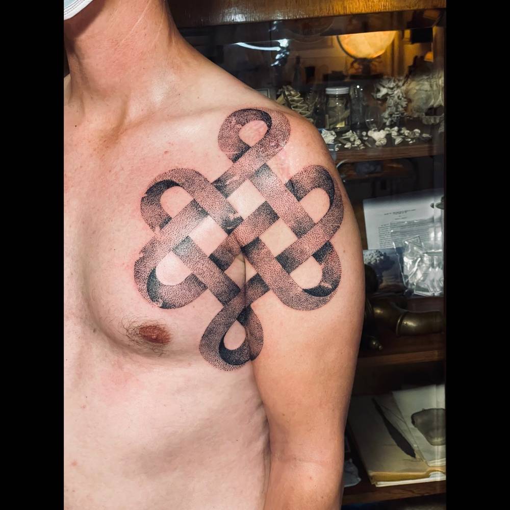 Dotwork style endless knot tattoo located on the shoulder.