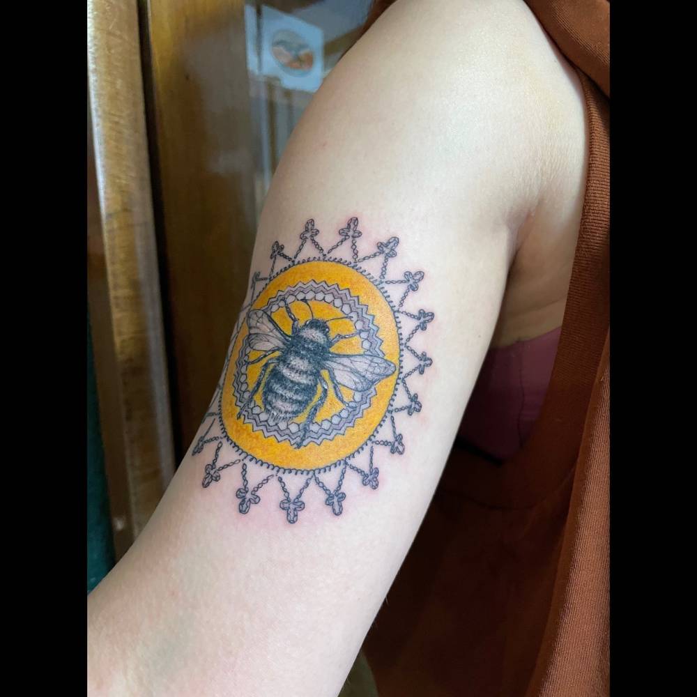 Illustrative style bee tattoo located on the bicep.