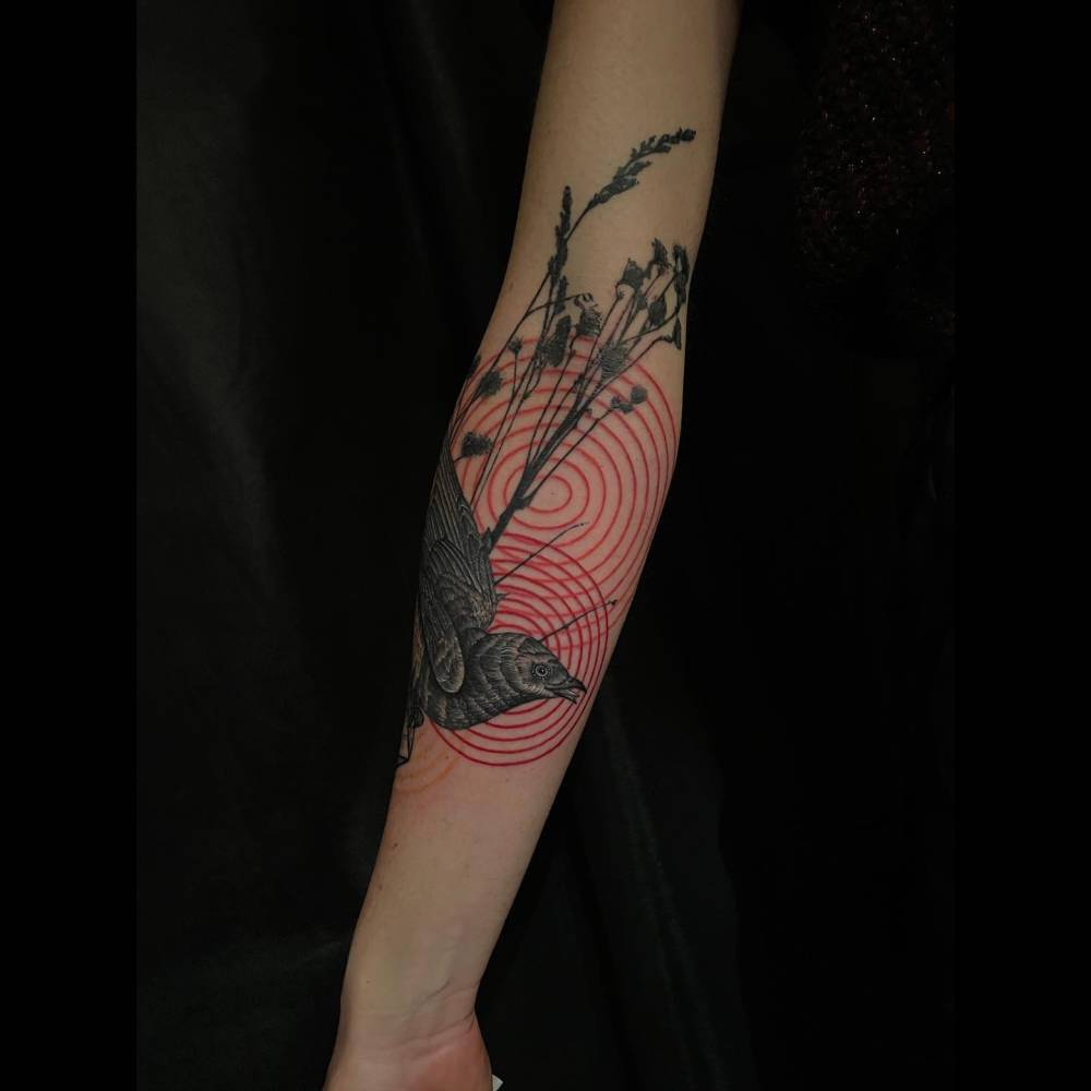 Graphic style bird tattoo located on the inner forearm.