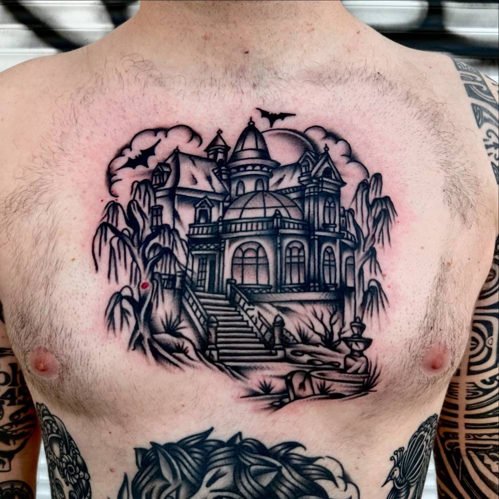 Traditional style haunted house tattoo located on the chest.