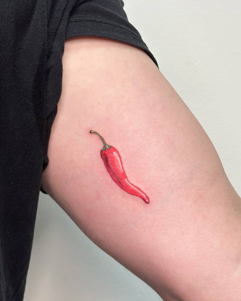 Illustrative style red chili tattoo located on the inner arm.