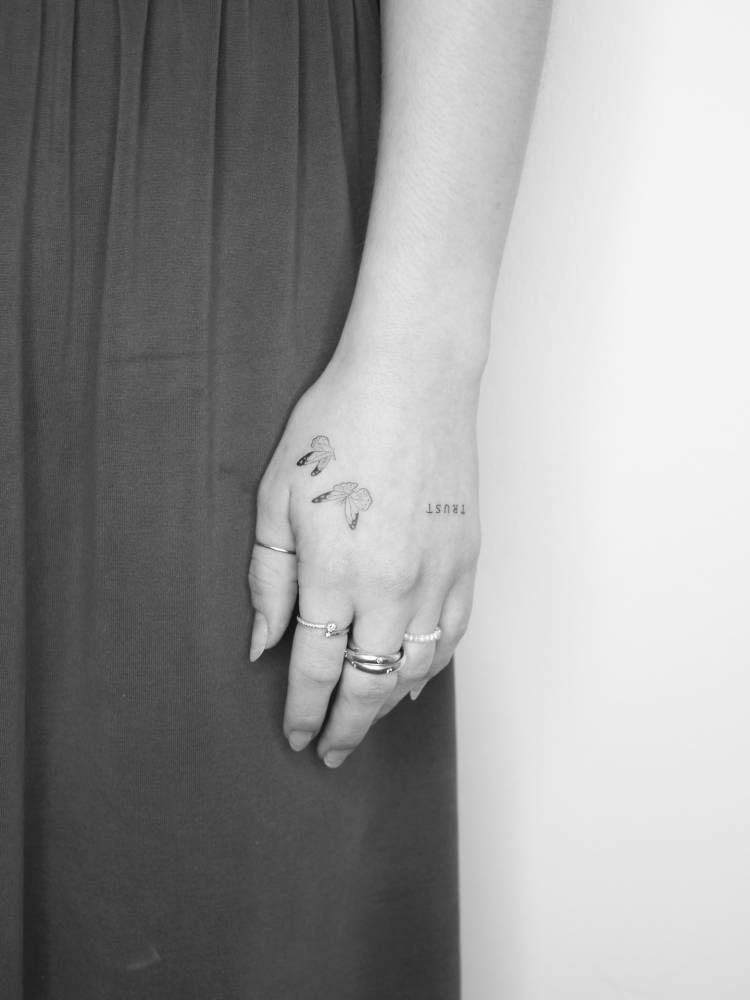 Fine line style butterfly couple tattoo located on the hand.