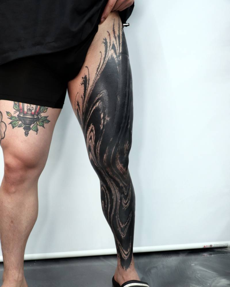 Abstract leg sleeve cover-up tattoo in blackwork style.