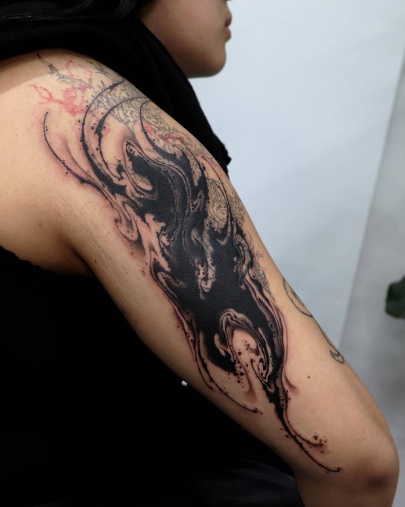 Abstract flow cover up tattoo done on the tricep.