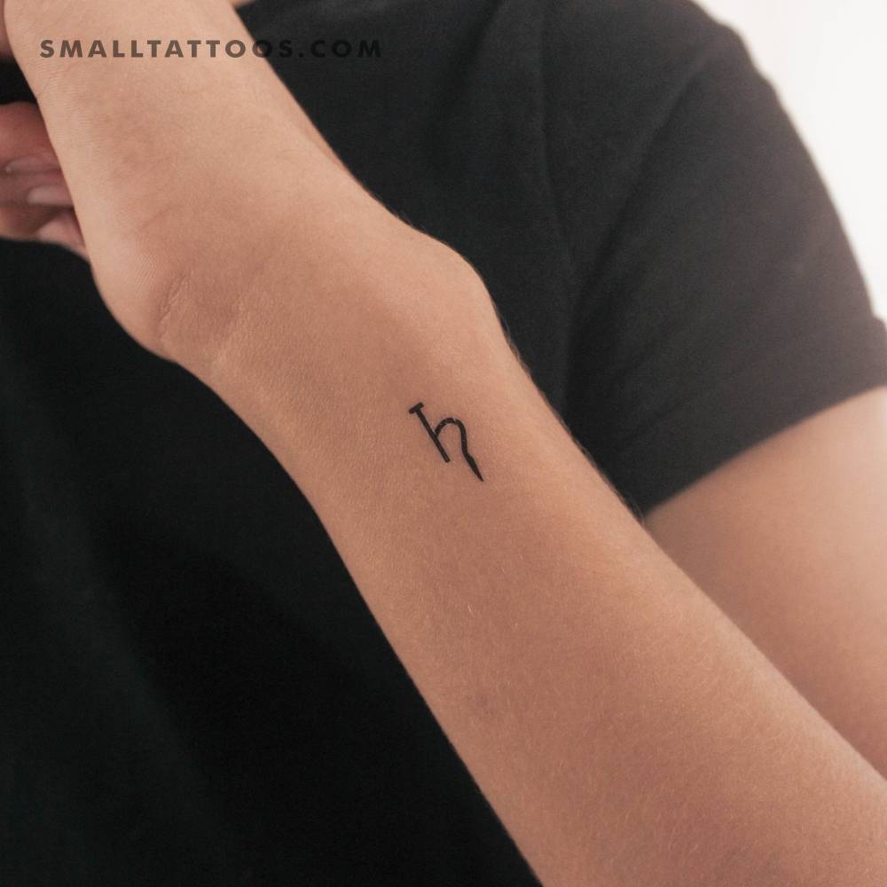 Minimalistic Saturn planetary symbol temporary tattoo located on the wrist.