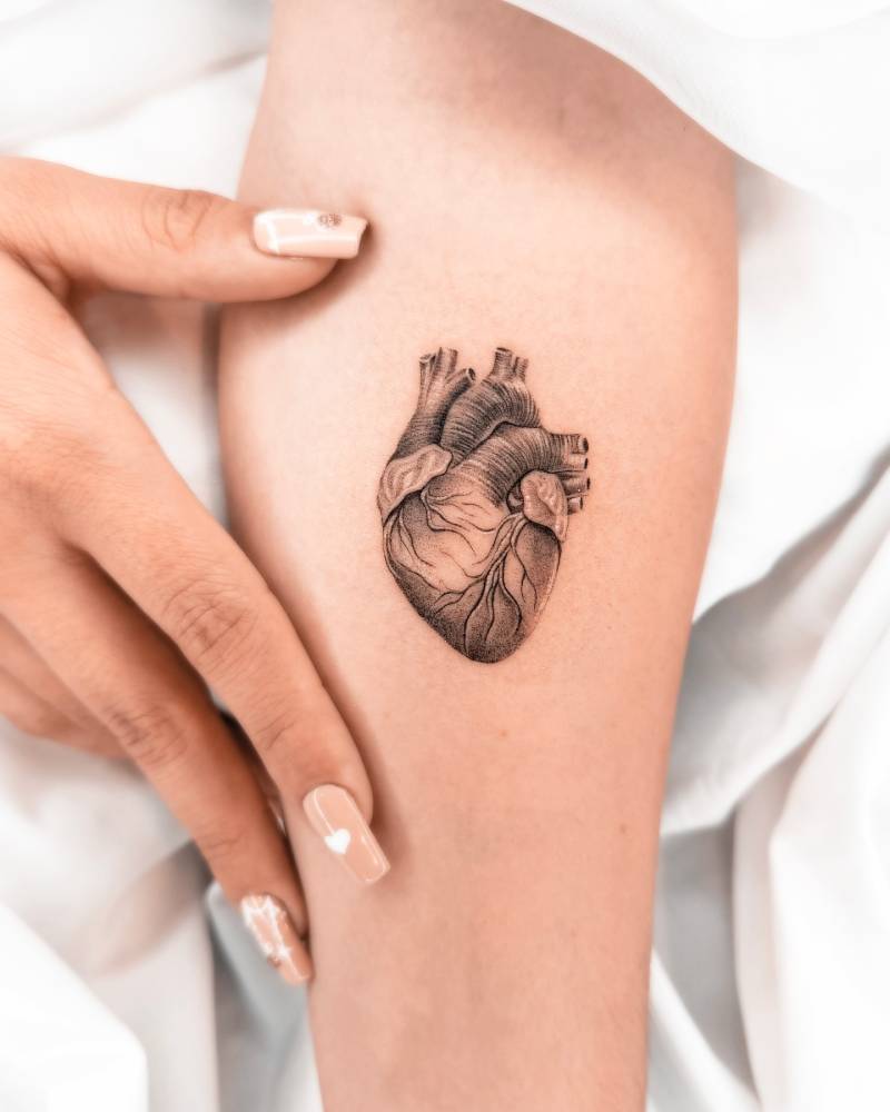 Anatomical heart tattoo in black and grey style placed on the inner forearm.