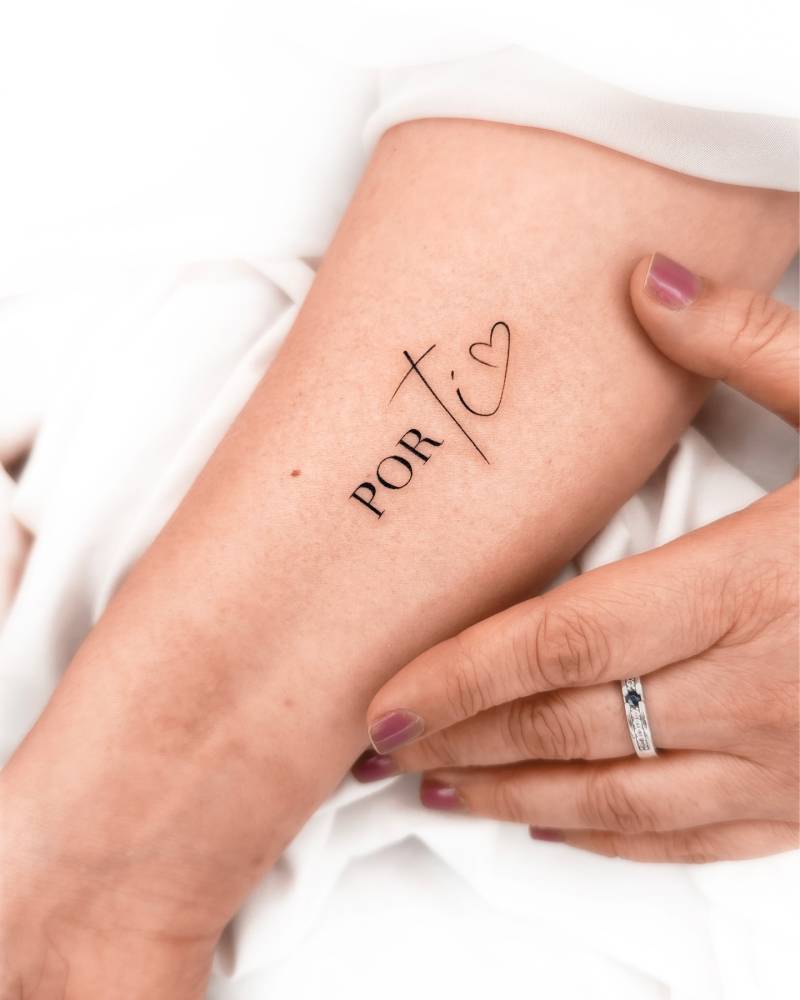 "Por ti" lettering tattoo located on the inner forearm.