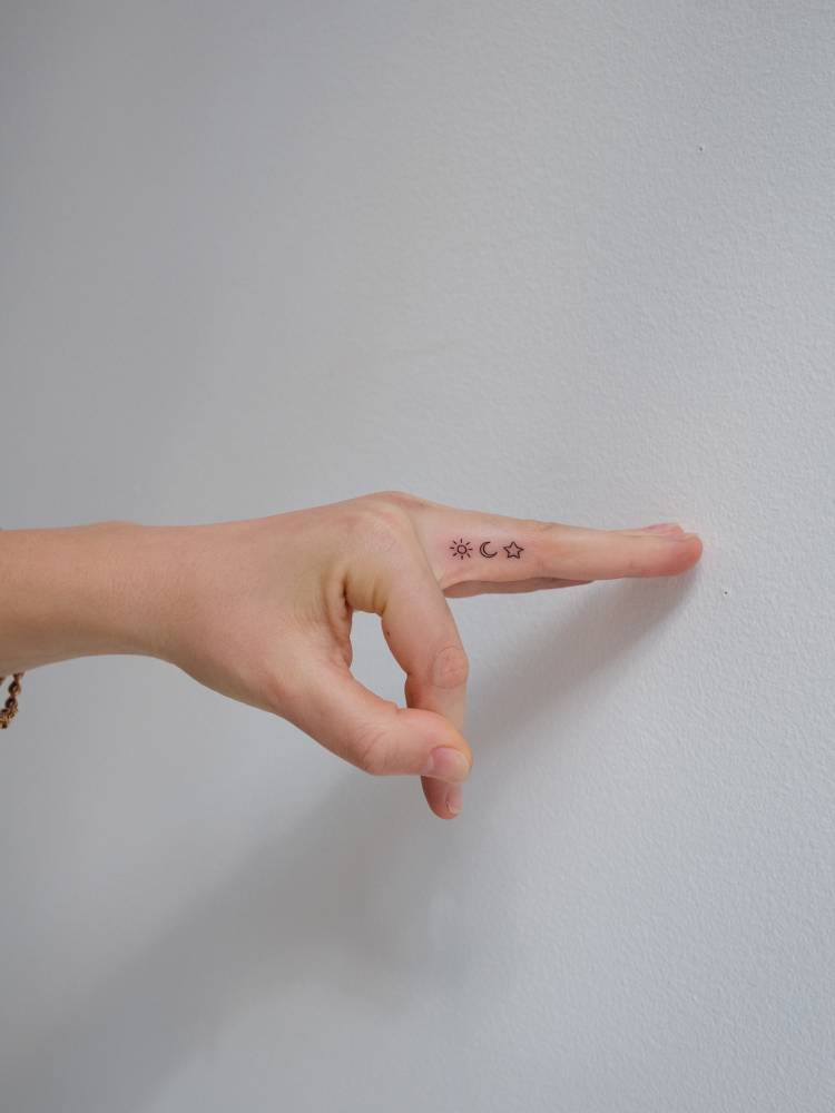 Sun, moon and star tattoo in minimalistic style located on the finger.