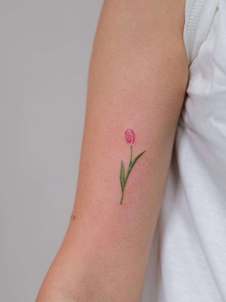Watercolor style tulip tattoo located on the bicep.