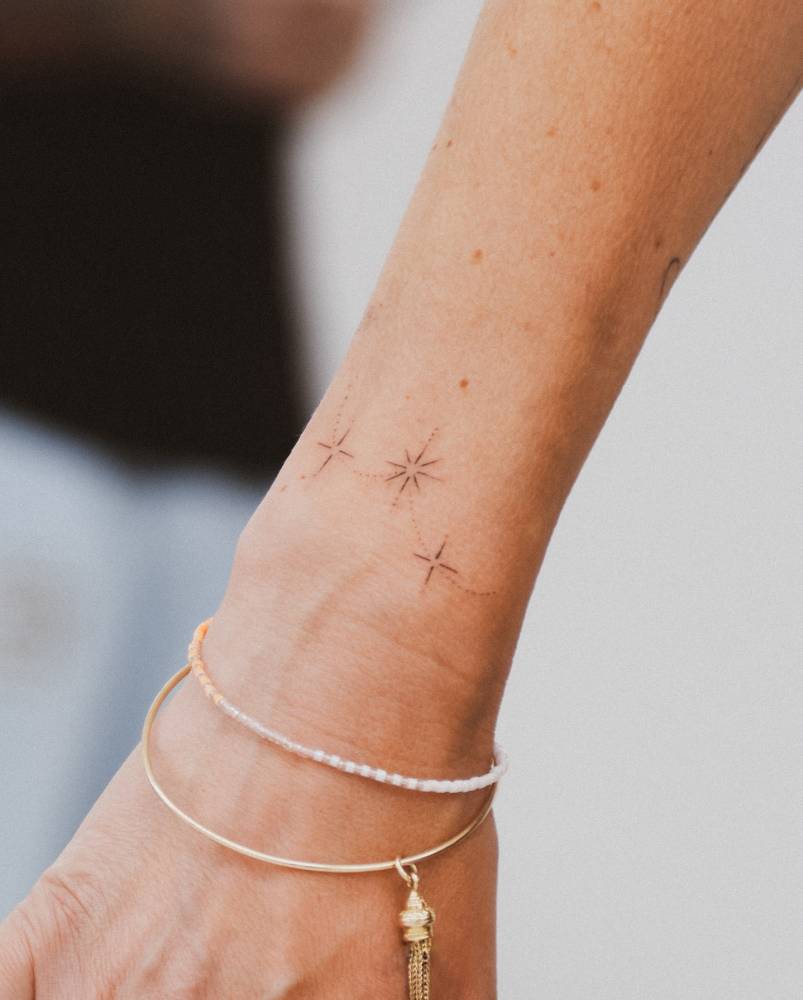 Minimalistic style sparkling stars tattoo located on the wrist.