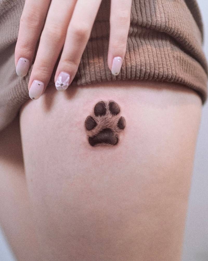 Micro-realistic style dog paw print tattoo done on the thigh.