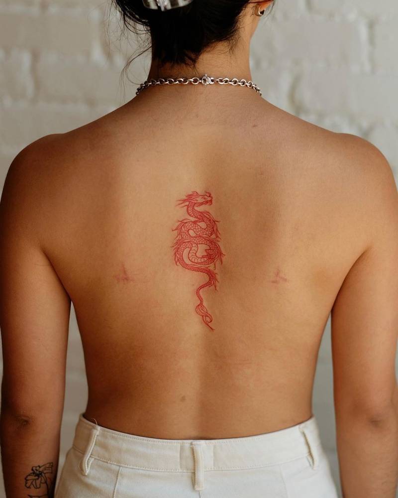Fine line red dragon tattoo located on the upper back.