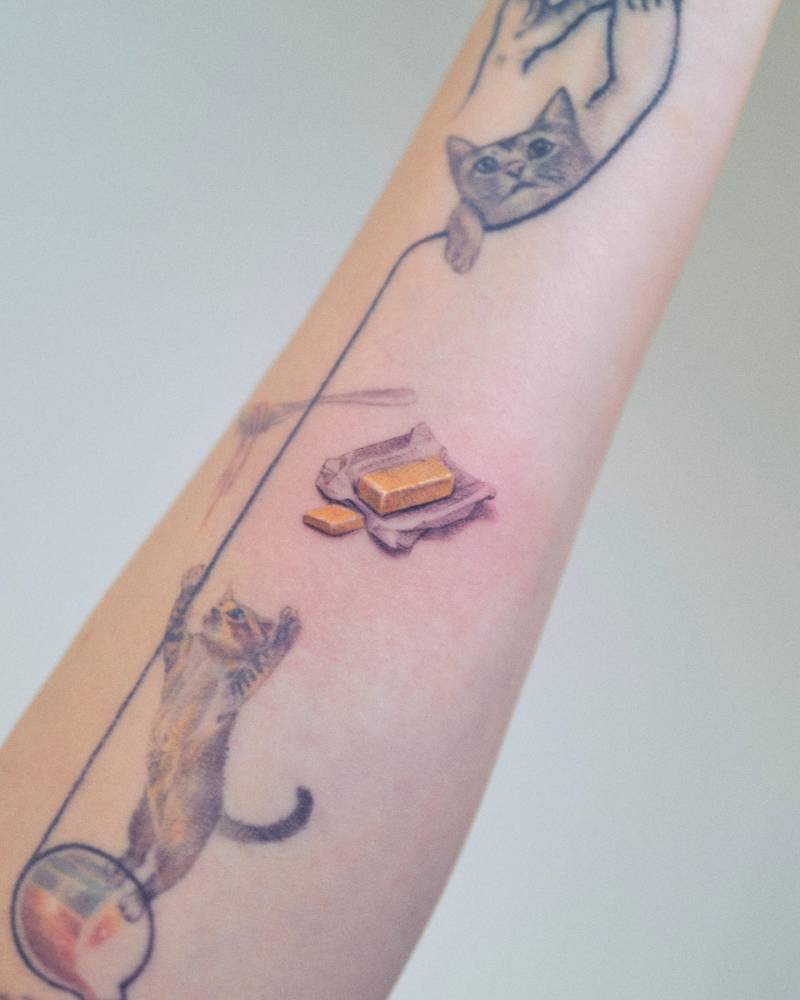Micro-realistic style tattoo of a butter stick located on the inner forearm.