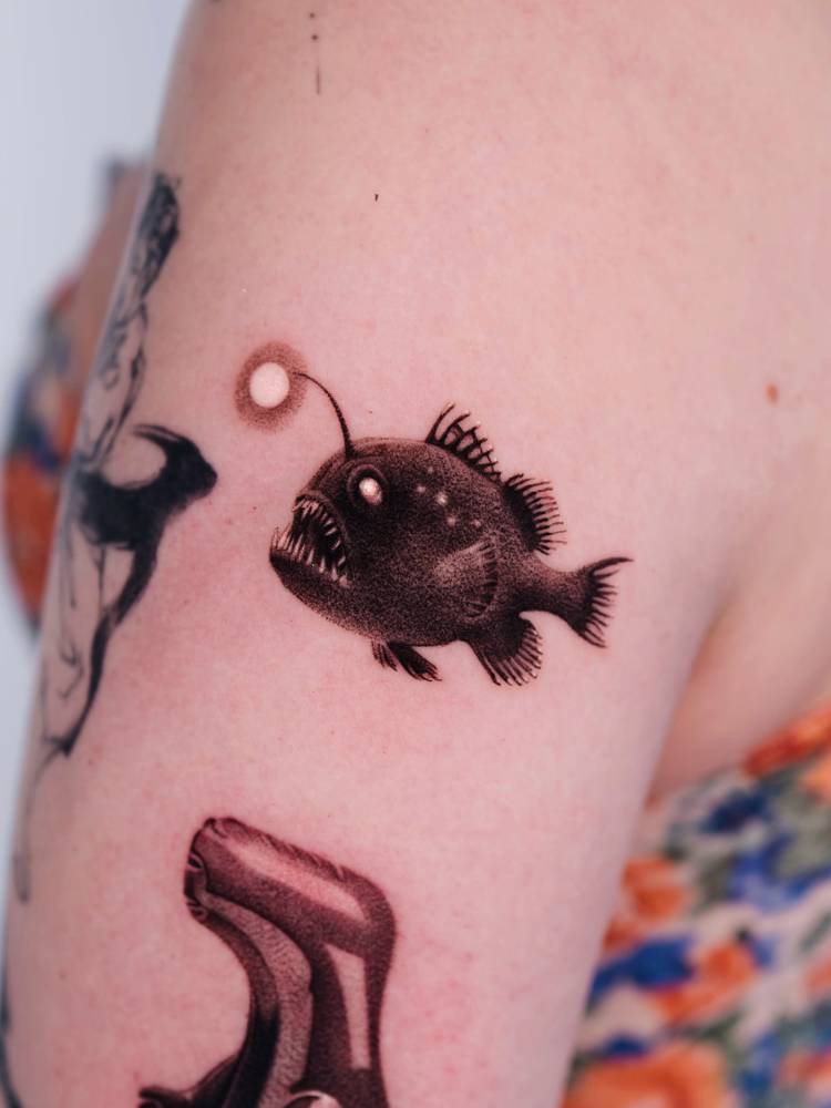 Anglerfish tattoo located on the upper arm, micro-realistic style.