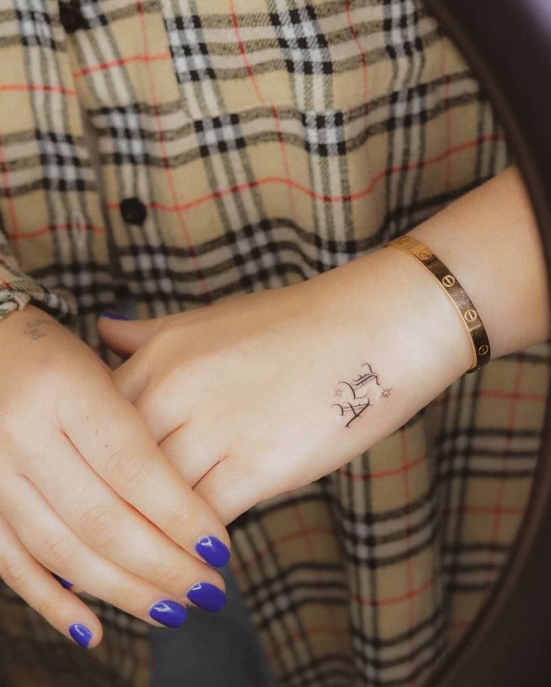 "LA" lettering tattoo in gothic font placed on the hand.