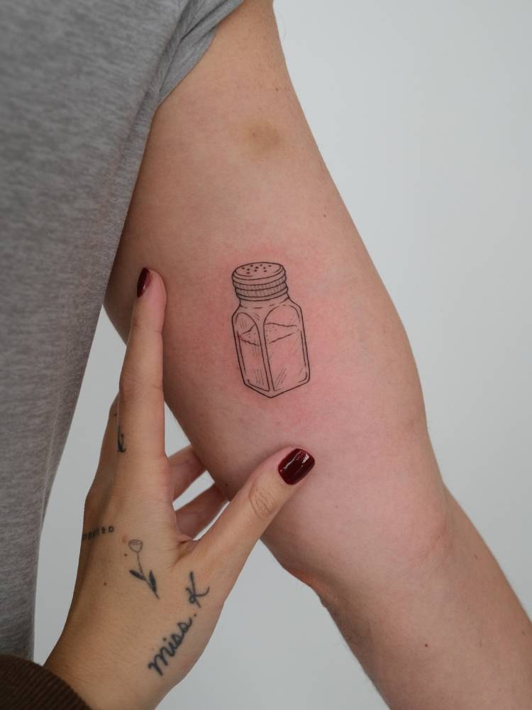 Salt shaker tattoo placed on the inner arm, done in fine line style.