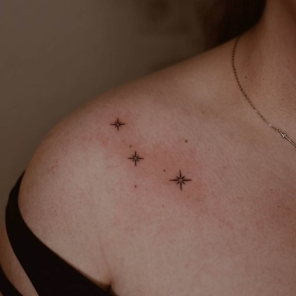 Sparkling stars tattoo in minimalistic style placed on the collarbone.