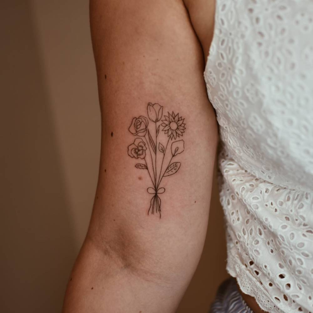 Flower bouquet tattoo in fine line style located on the inner arm.