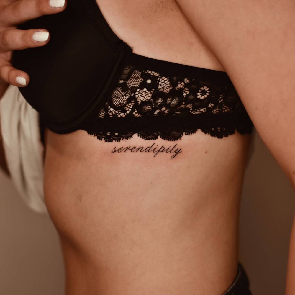 Lettering tattoo of the word "serendipity" located on the rib.